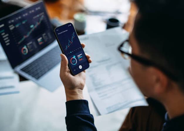 A person analyzing stock market data on a smartphone.